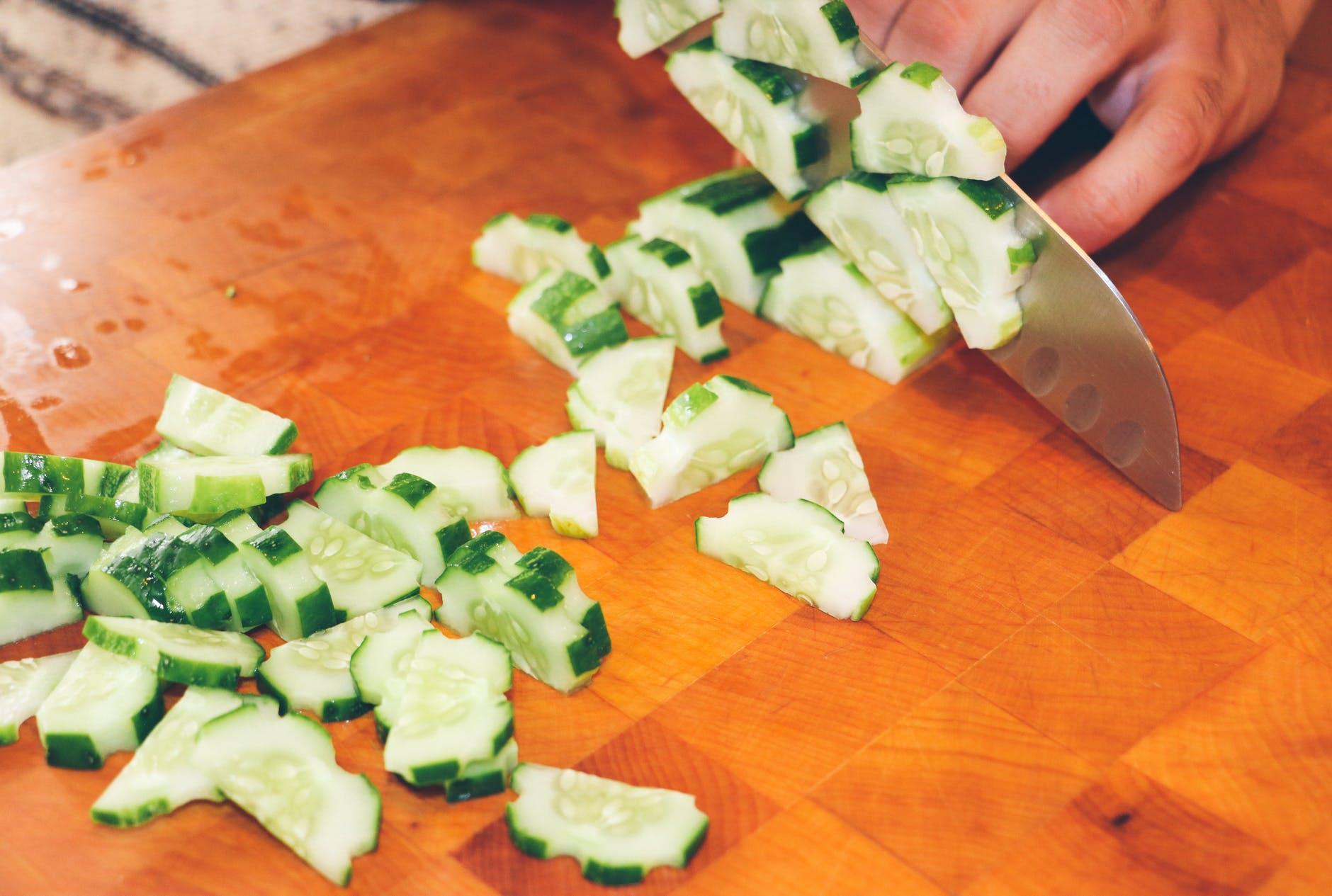 person slicing cucumber vegetable