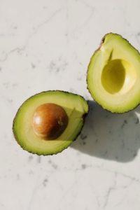 halves of fresh green avocado on marble surface keto snacks